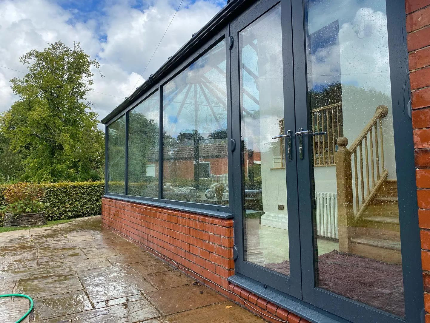 Anthracite-framed conservatory with French doors on a red-brick house