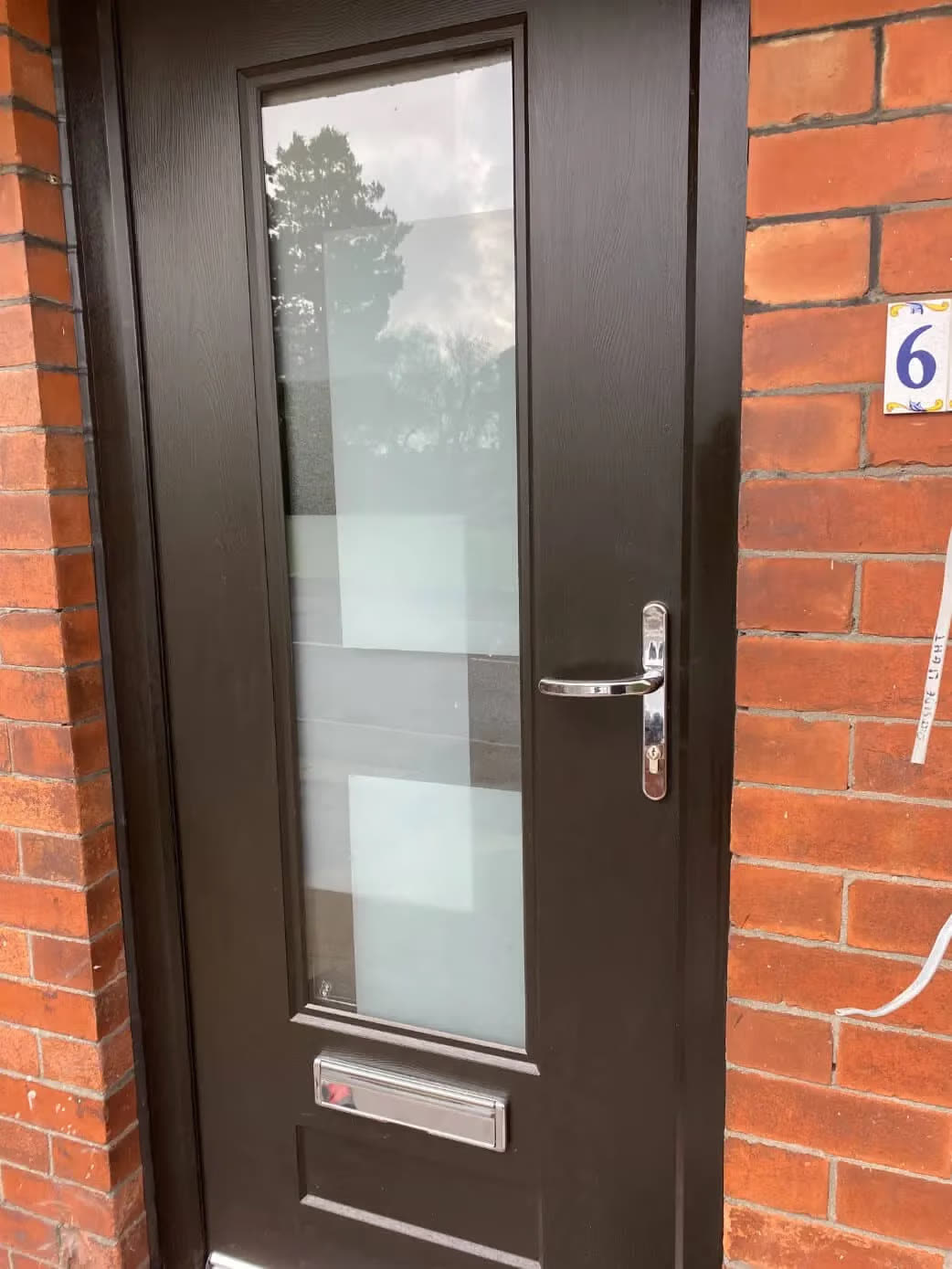 Dark composite front door with patterned glass on house number 6