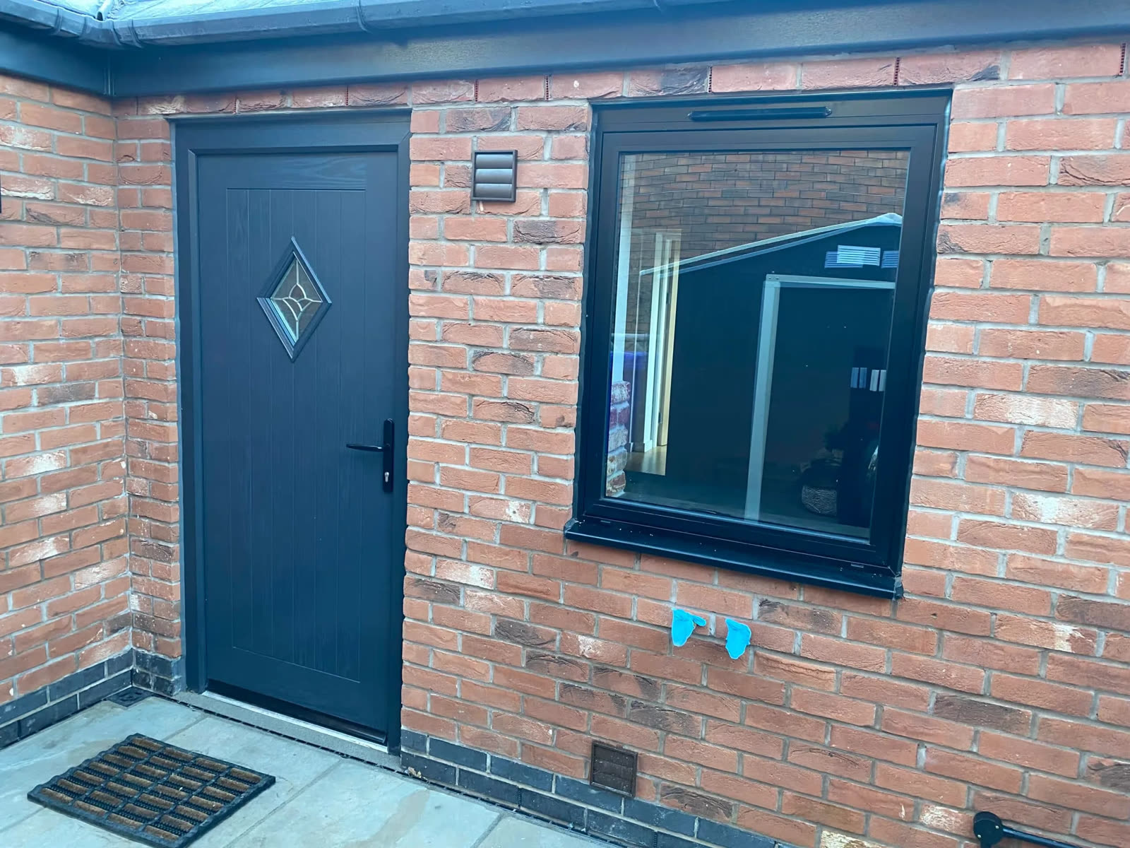 Anthracite composite door and matching window on a red-brick house