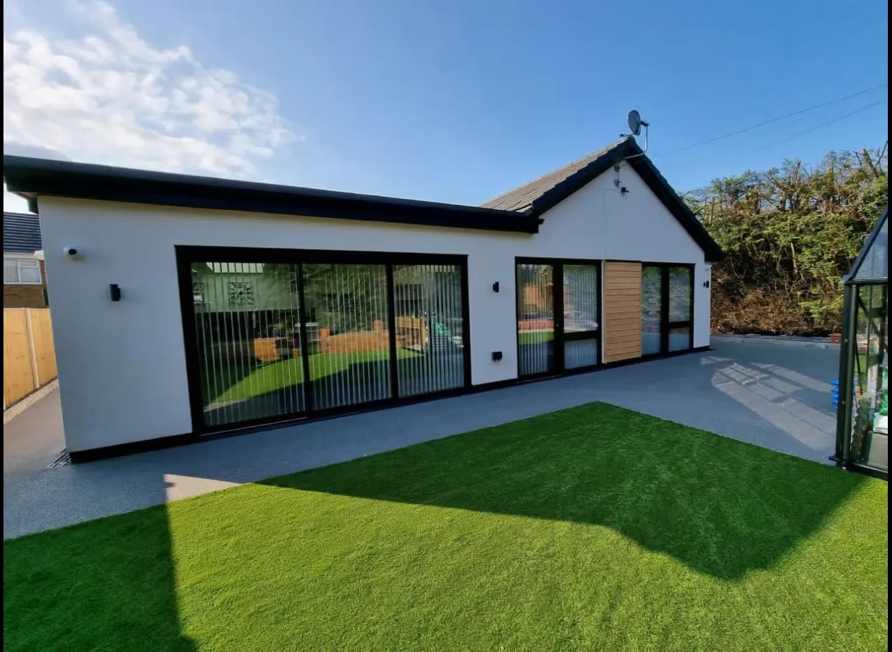 Black-framed sliding doors on a white rendered garden extension